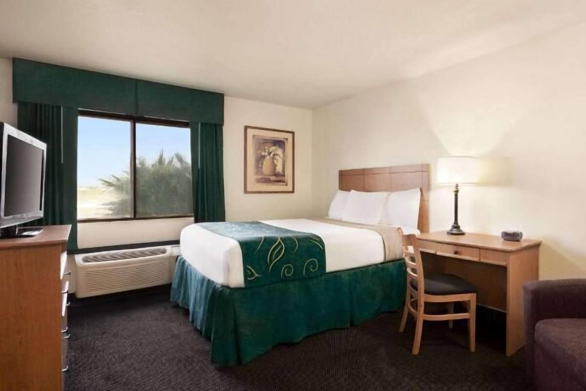 A hotel room with a bed, a desk, a chair, a television, and a window with a view.