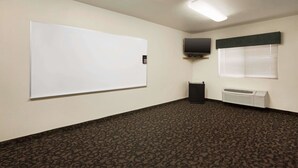 Ett konferensrum med en whiteboardtavla, en platt-TV och ett fönster med persienner.