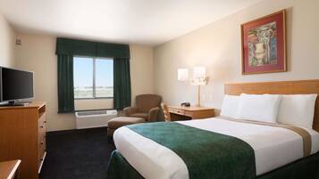 A hotel room with a bed, a desk, a chair, a television, and a window with curtains.