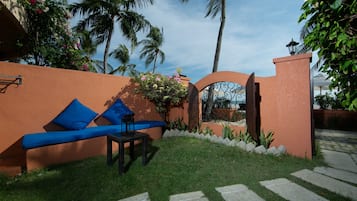 A patio with a blue sofa and table, surrounded by palm trees and a stone pathway.
