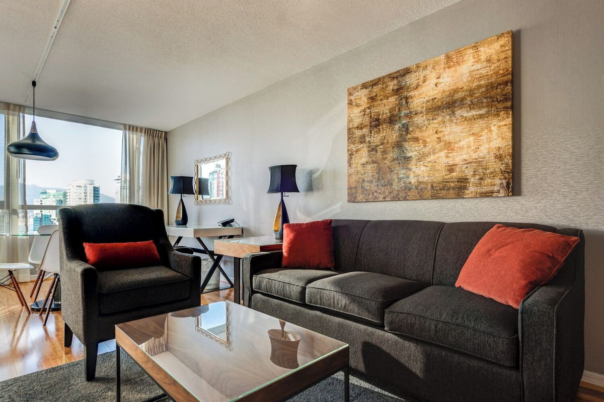 A modern living room with a sofa, armchairs, a coffee table, and a desk with lamps.