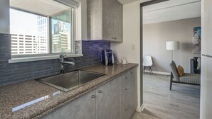 A modern kitchen with granite countertops, a stainless steel sink, and a window overlooking a cityscape.