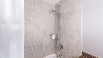 Un baño moderno con paredes de baldosas estampadas, ducha con cabezal de ducha manual y bañera blanca con grifo de cromo.