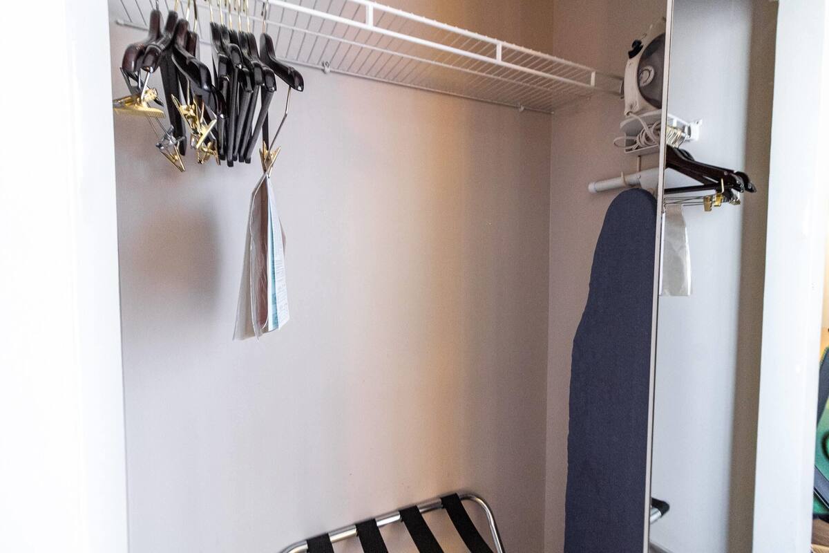 Una habitación con una pared blanca, un estante metálico con diversos objetos y un objeto azul grande a la derecha.