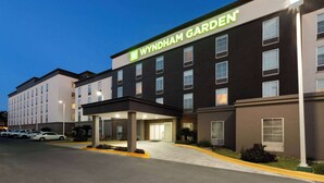 Ein Wyndham Garden Hotel mit moderner Fassade, mehreren Etagen und einem Parkplatz mit einigen Autos.
