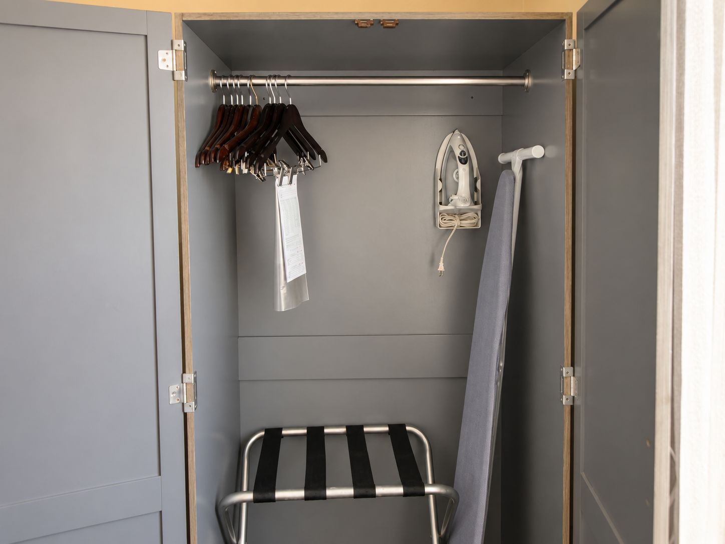 Un vestidor con perchero, plancha y toallero.