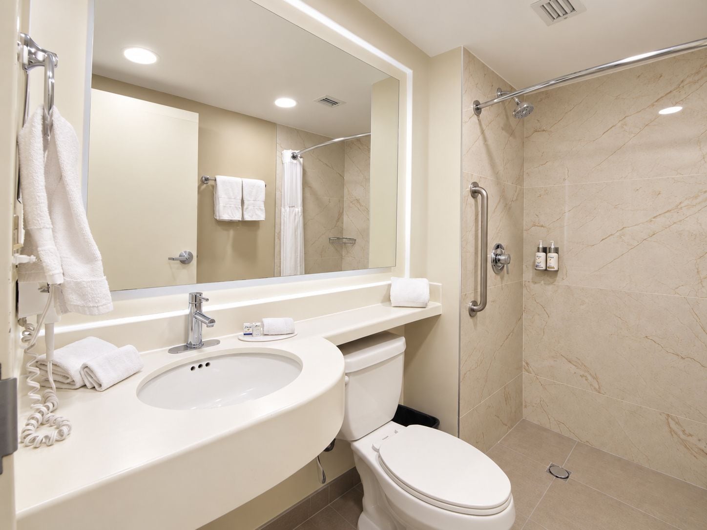 A bathroom with a sink, toilet, mirror, and shower area.