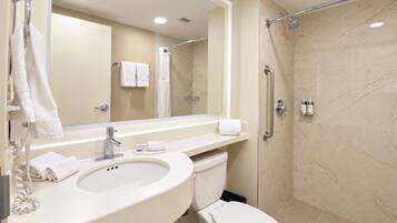 Un baño con lavamanos, inodoro, espejo y zona de ducha.
