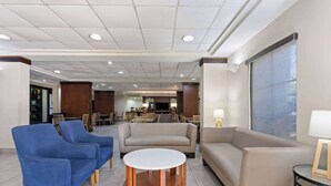 Eine moderne Lobby mit blauen Sesseln, einem runden Couchtisch und einem beigefarbenen Sofa.