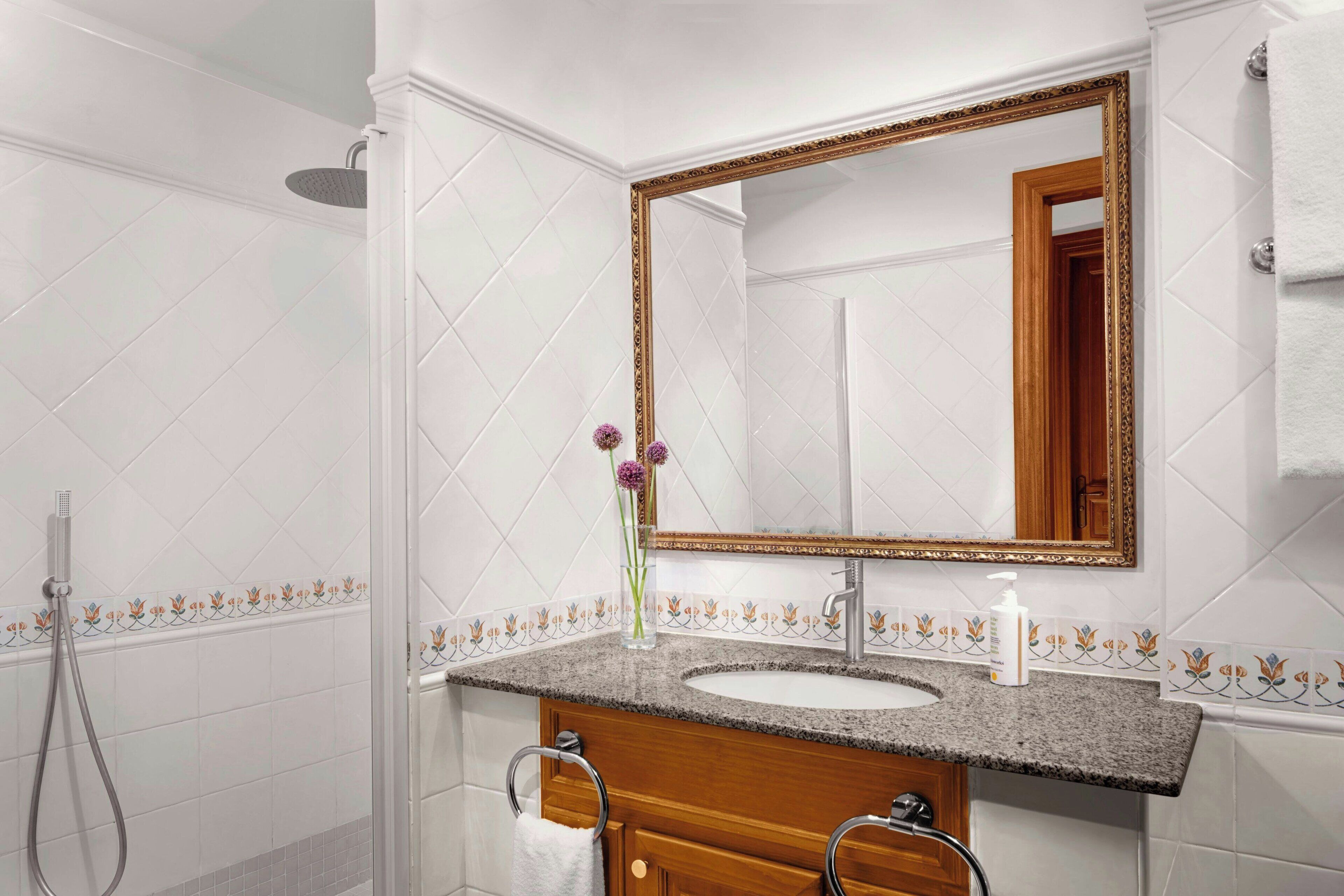 A bathroom with a sink, mirror, and shower.