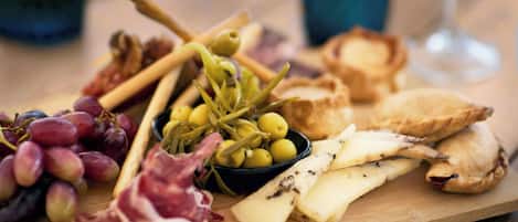 Una tabla de madera con varios quesos, uvas, aceitunas y galletas.