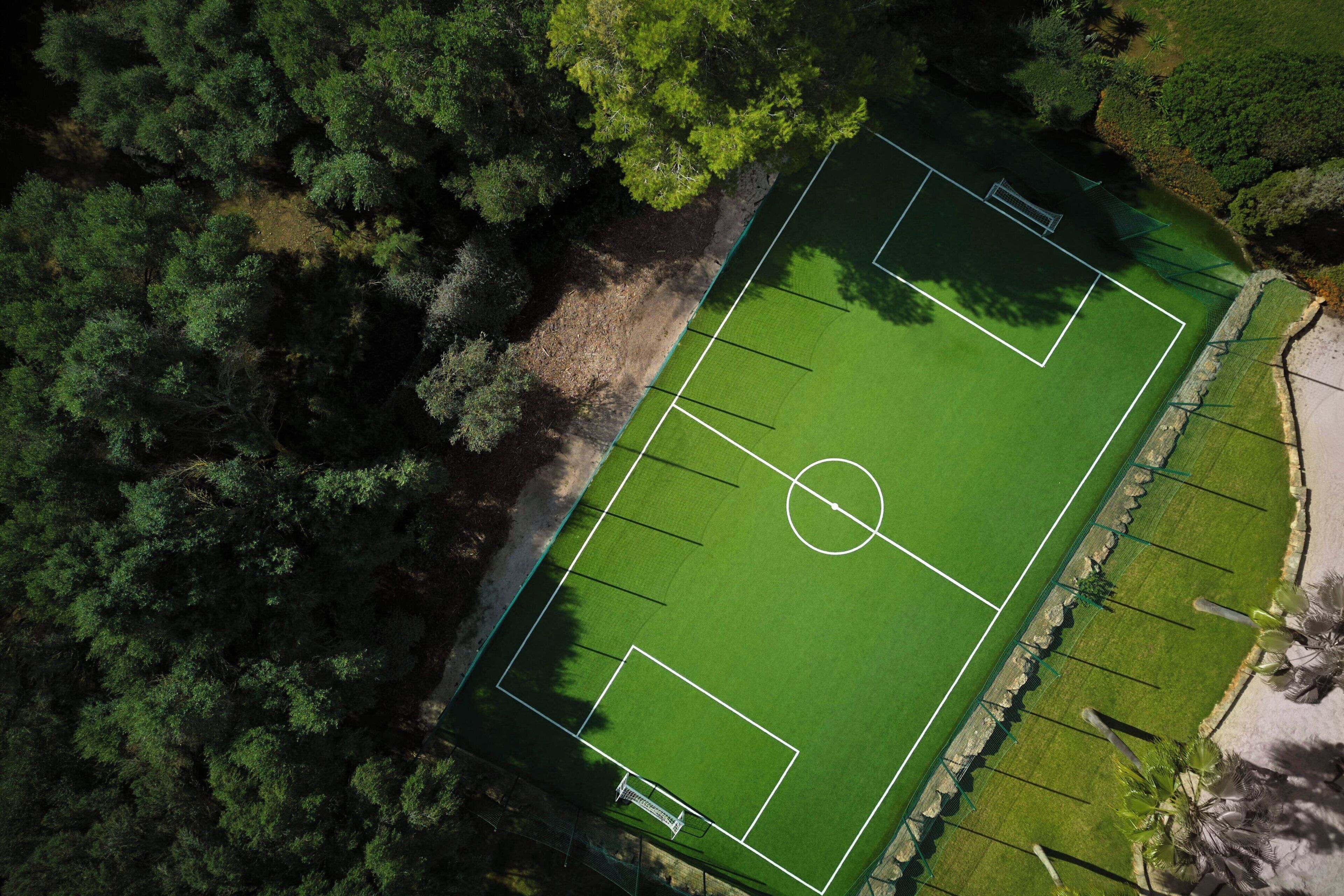 Vue aérienne d’un court de tennis entouré d’une forêt dense.