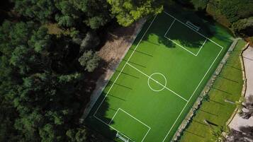 Vista aèria d'una pista de tennis envoltada per un bosc dens.