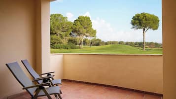 Ein Balkon mit zwei Liegestühlen und Blick auf einen Golfplatz.