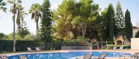 Una piscina con sillones de descanso y una valla.