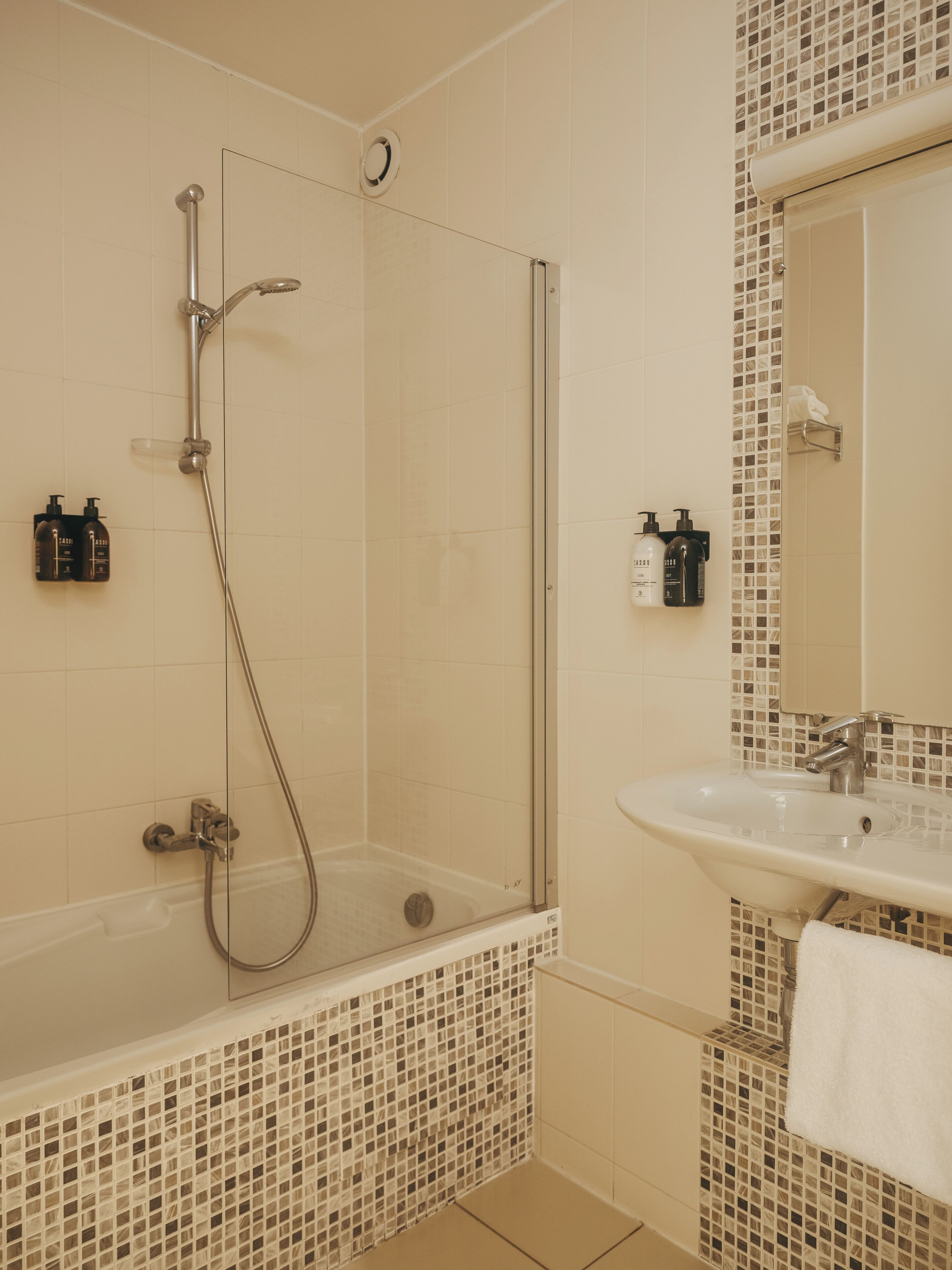 A bathroom with a glass-enclosed shower, a sink, and a tiled mosaic backsplash.
