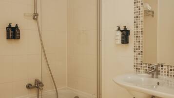 A bathroom with a glass-enclosed shower, a sink, and a tiled mosaic backsplash.