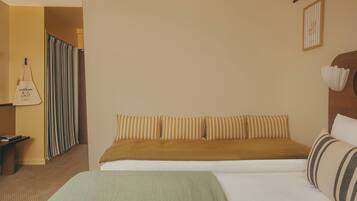 Una habitación de hotel con una cama, una mesita de noche, una maleta y una cortina a rayas.