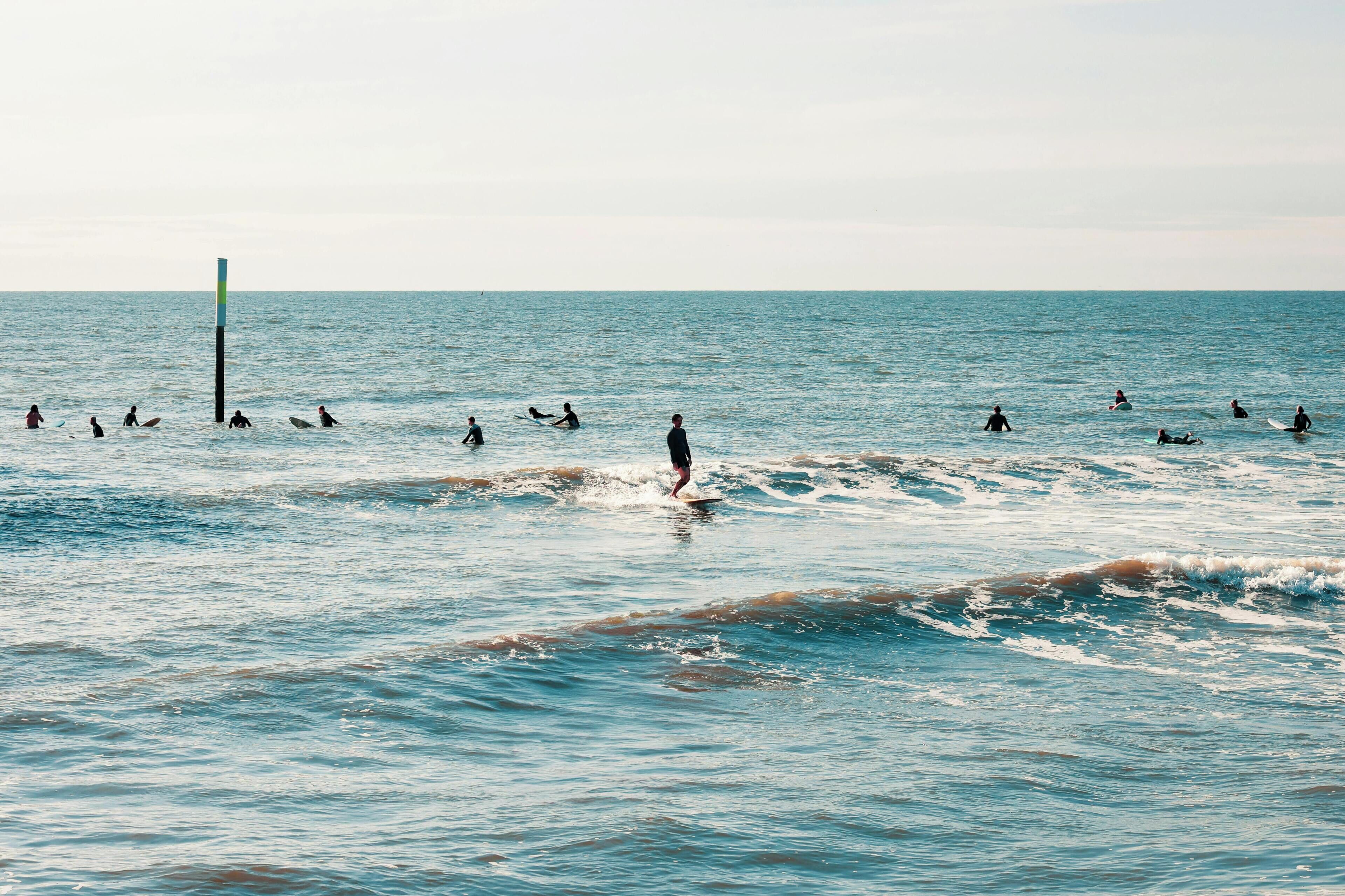 A coastal scene with surfers in the water and a buoy in the distance.