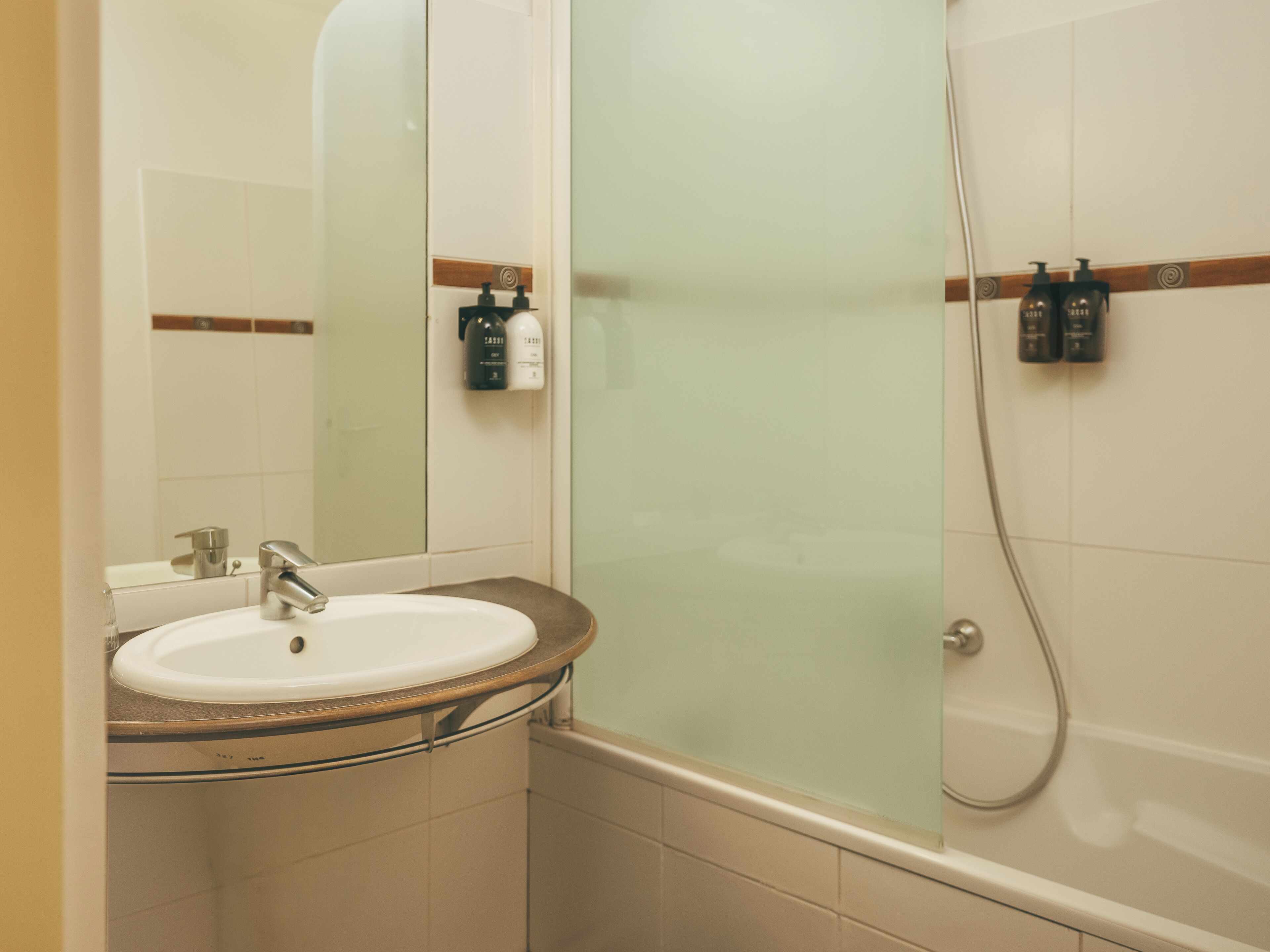 Une salle de bain avec un lavabo, un miroir et une douche en verre.