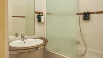Une salle de bain avec un lavabo, un miroir et une douche en verre.