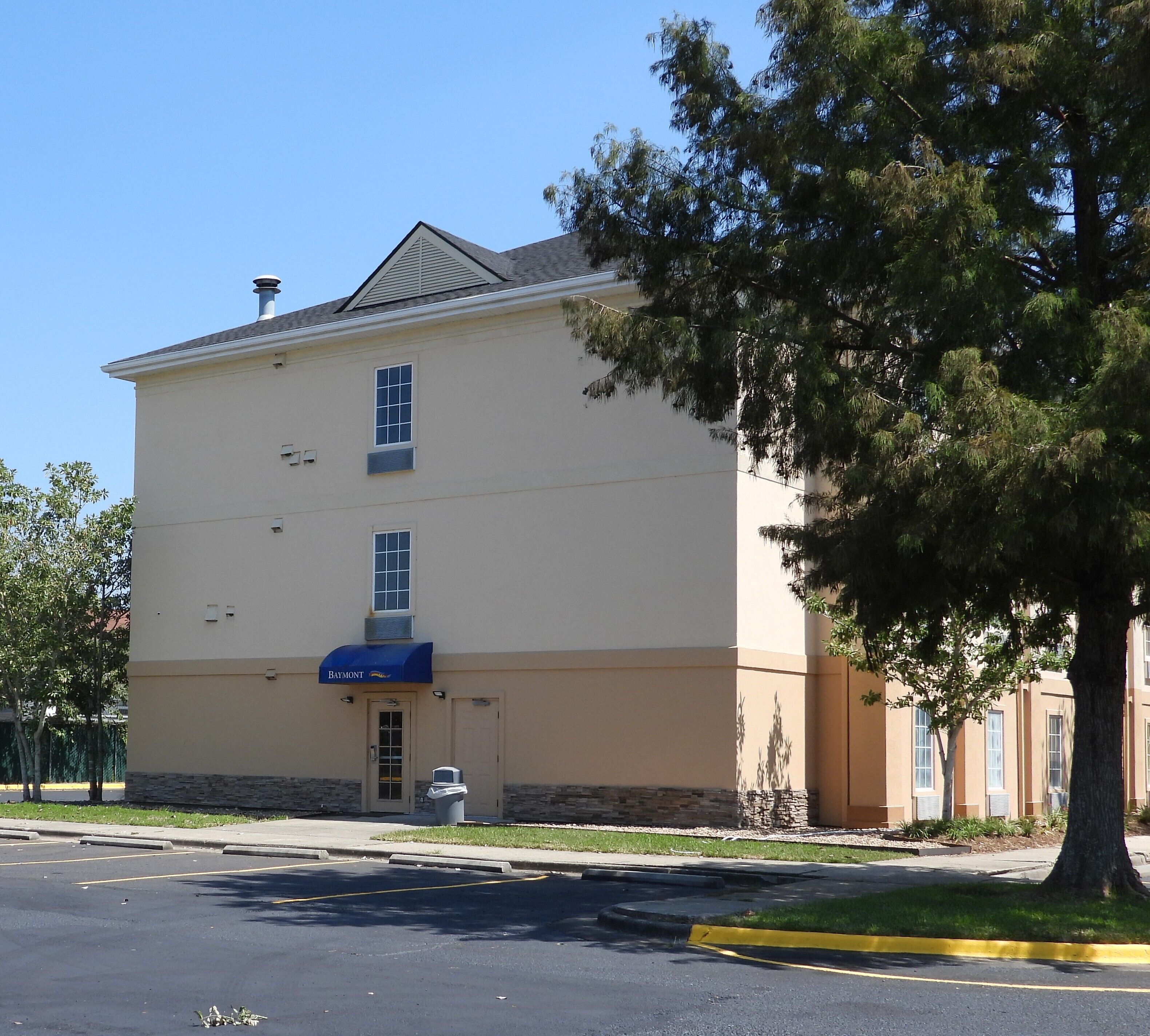 A two-story building with a flat roof, a blue awning, and a small front entrance.