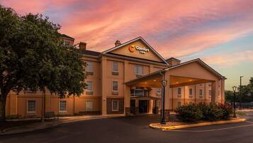 Ein Comfort Inn Hotel mit überdachter Eingangspartie, Parkplatz und einem Baum links.