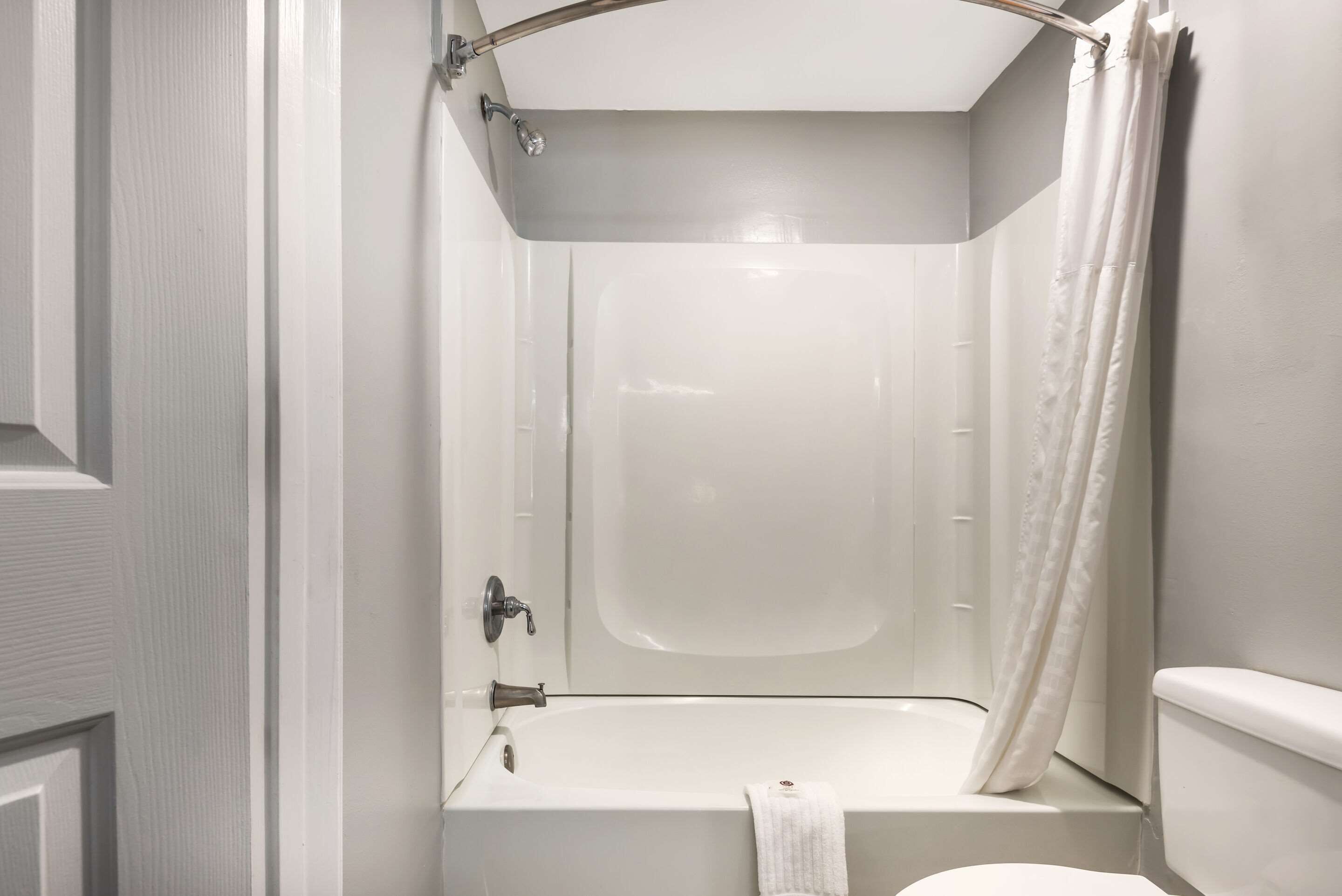 A small, white bathroom with a bathtub, a toilet, and a shower curtain.