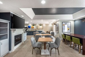 Una cocina moderna con televisión de pantalla plana, chimenea y comedor con mesa y sillas.