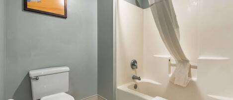 A bathroom with a toilet, a bathtub, and a shower curtain.
