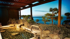 A hot spring area with a wooden deck, stone basin, and a view of the ocean. - Paradise Hotel Busan (Busan)
