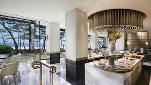 Un moderno vestíbulo de hotel con una recepción de mármol, zona de estar y vistas al mar.