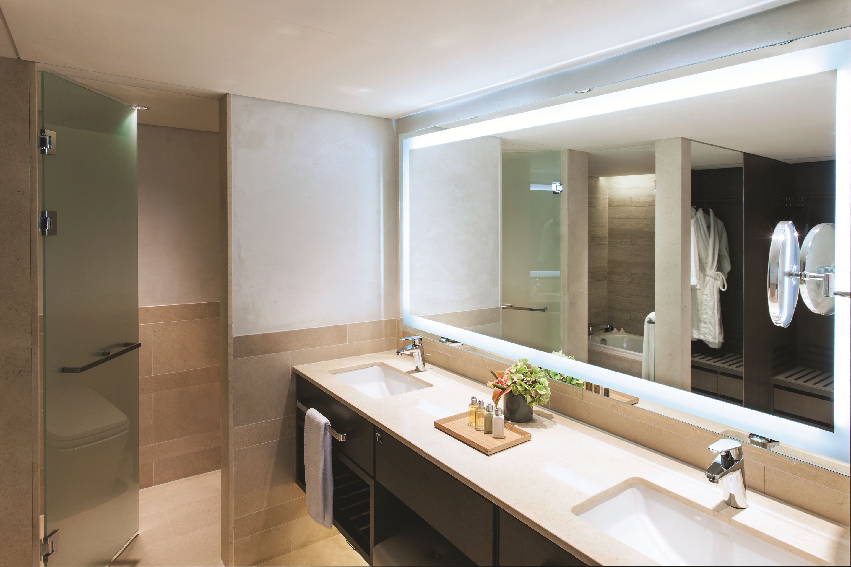 Un baño moderno con dos lavamanos, un espejo grande y una cabina de ducha con mampara de vidrio.