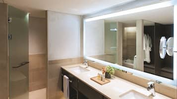 A modern bathroom with two sinks, a large mirror, and a glass shower enclosure.
