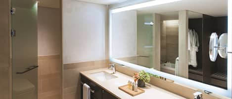 Un baño moderno con dos lavamanos, un espejo grande y una cabina de ducha con mampara de vidrio.