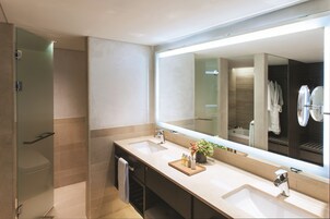 A modern bathroom with two sinks, a large mirror, and a glass shower enclosure.