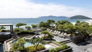 Un resort con piscina, sillones de descanso y vistas al mar y las montañas.