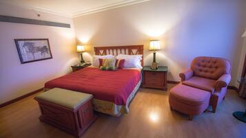 Un dormitorio ordenado con una cama grande, dos mesitas de noche con lámparas, una silla y una pequeña mesa.