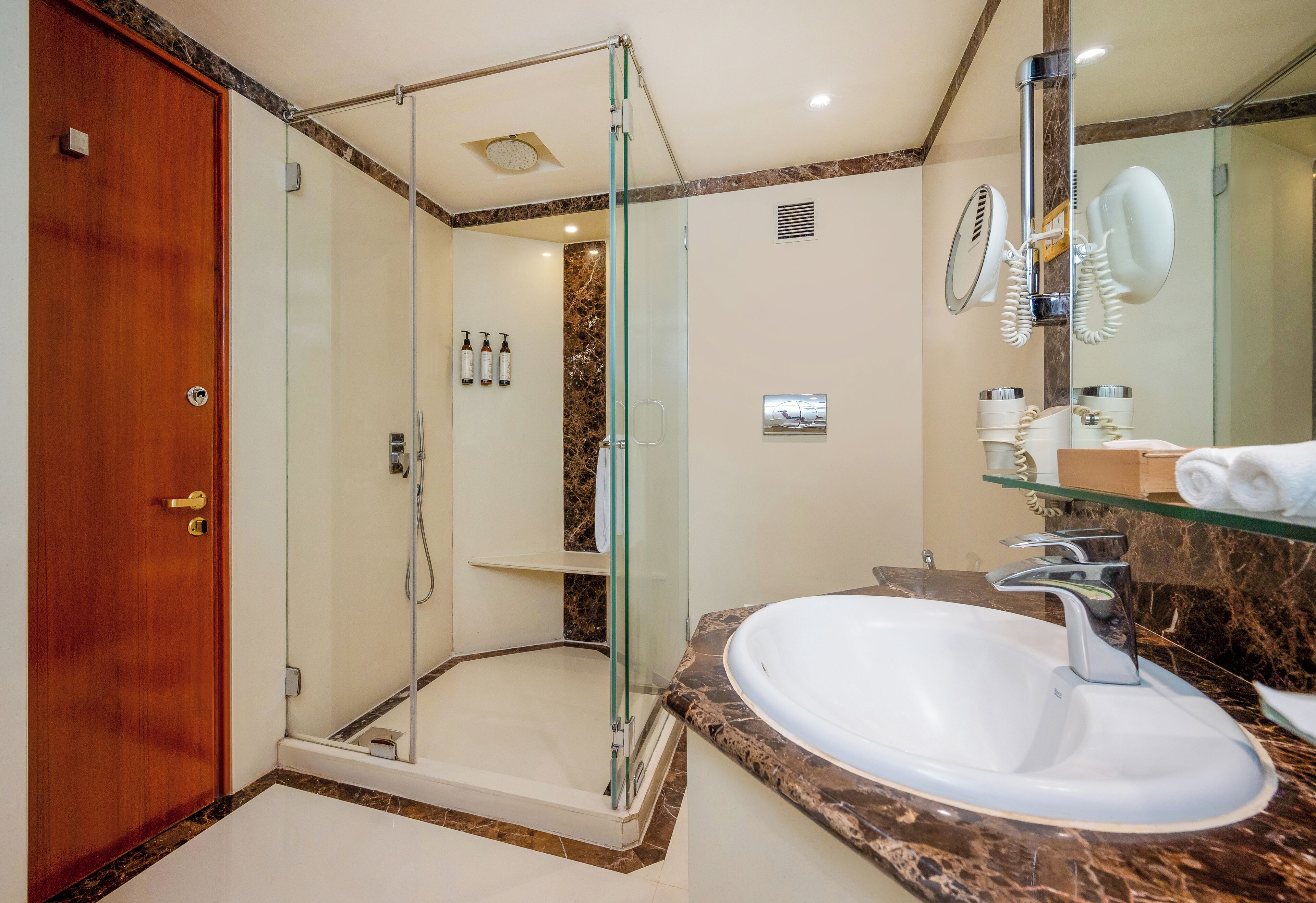 A modern bathroom with a glass-enclosed shower, a marble countertop sink, and a large mirror.