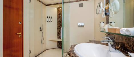 A modern bathroom with a glass-enclosed shower, a marble countertop sink, and a large mirror.