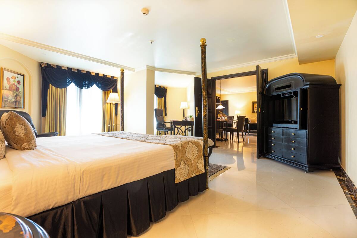 Een hotelkamer met een groot bed, een bureau, een stoel, een televisie en een minibar.