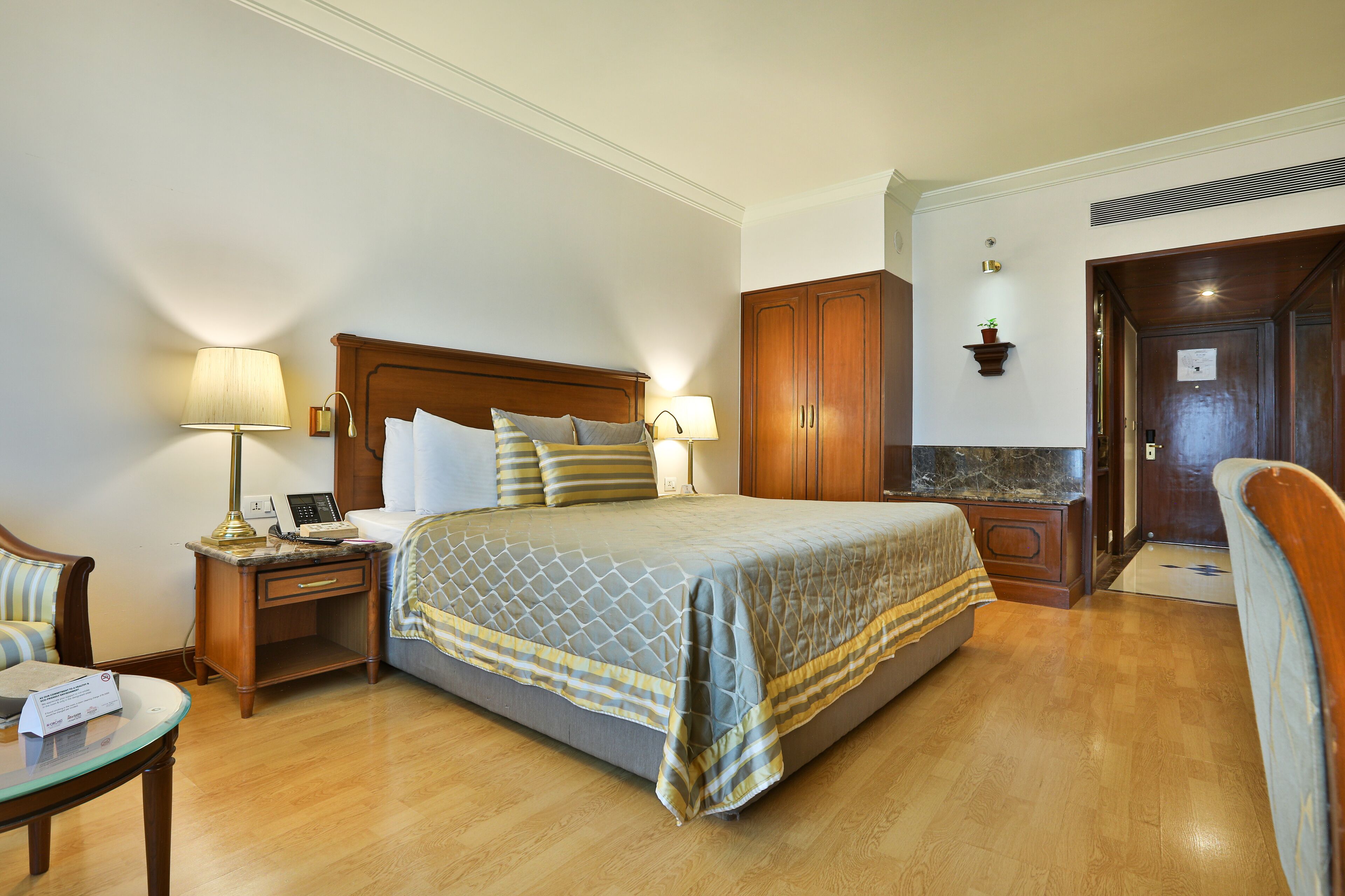 Una habitación de hotel con una cama grande, mesitas de noche, una silla y un escritorio.