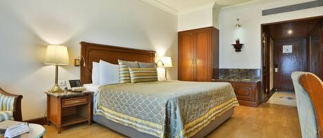 Una habitación de hotel con una cama grande, mesitas de noche, una silla y un escritorio.