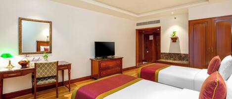 A hotel room with two beds, a desk with a television, a chair, and a mirror.