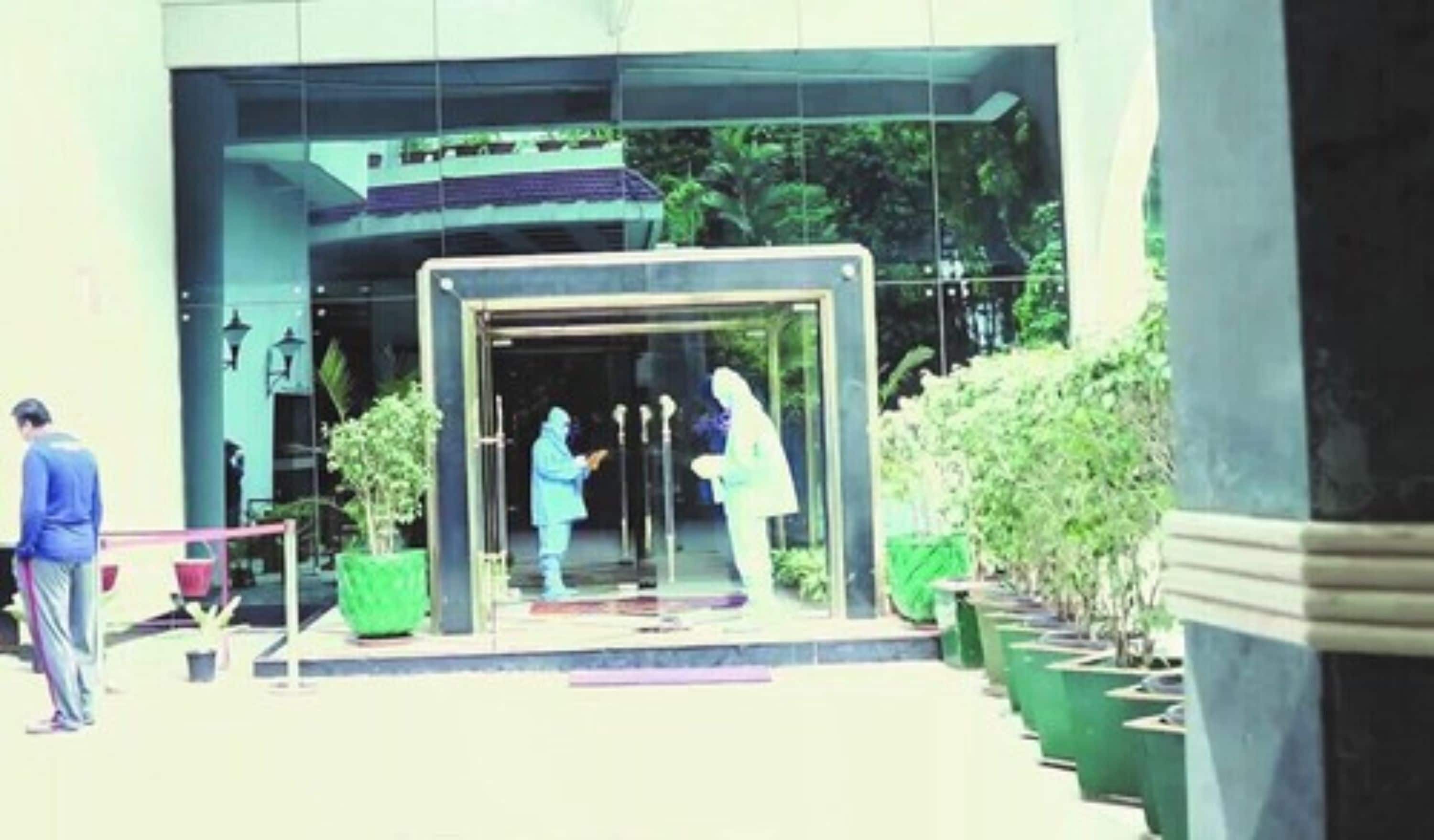 A building entrance with a glass door, potted plants, and a person standing outside.