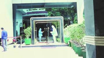 A building entrance with a glass door, potted plants, and a person standing outside.