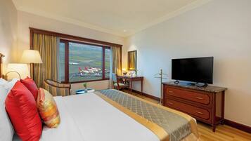 Habitación de hotel con una cama grande, un escritorio, un televisor y una ventana con vistas a aviones.