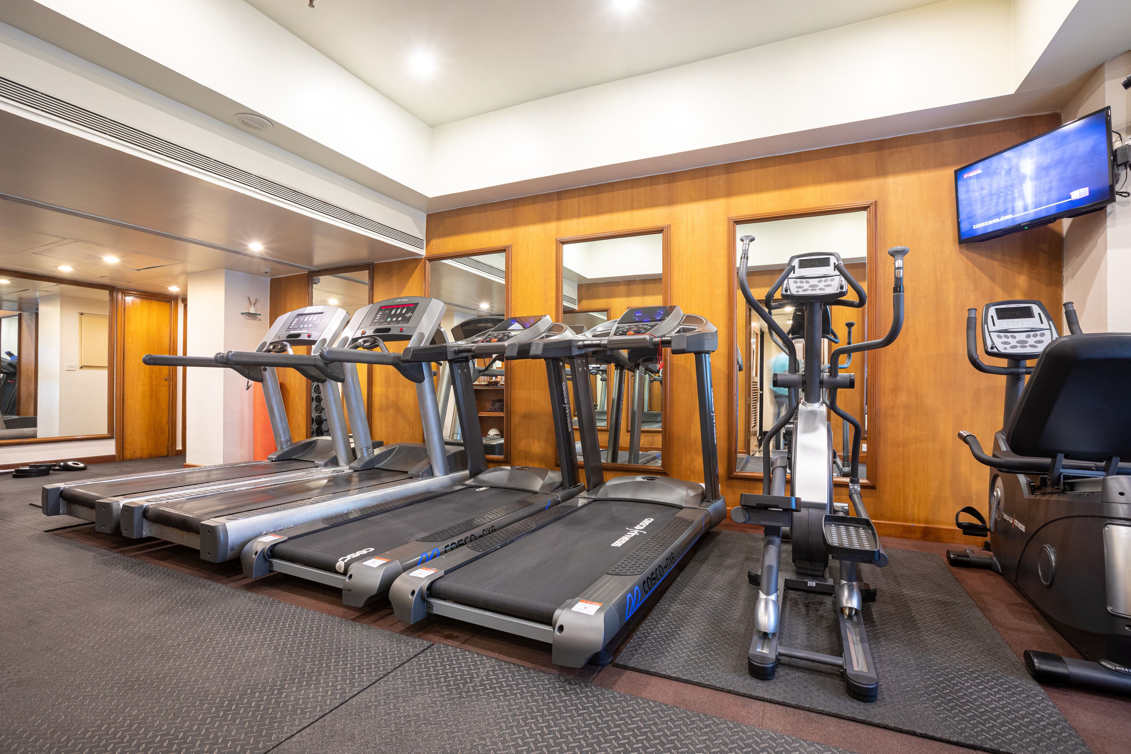 Un gimnasio con cintas de correr, elípticas y una bicicleta estática.