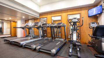 Un gimnasio con cintas de correr, elípticas y una bicicleta estática.