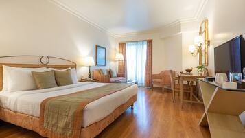 Ein Hotelzimmer mit einem großen Bett, einem Schreibtisch, einem Stuhl und einem Fernseher.